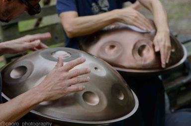 Mehrere Spieler sitzen zusammen und spielen gemeinsam Handpan