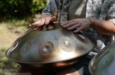 Handpan-Spieler sitzt im Schneidersitz und hält eine Handpan auf dem Schoß, bereit zum Musizieren